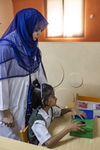 Yusra Arsalam, 7 and health worker playing as part of the rehabilitation and training process at the Center for Autism Rehabilitation and Training Sind (C-ARTS) in Karachi, Pakistan