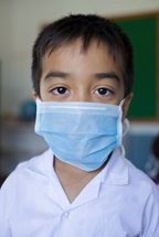A young boy, wearing a mask in a school in Nepal