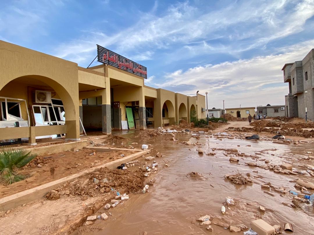 A hospital entrance on a flood-damaged street with muddy covering, in Libya