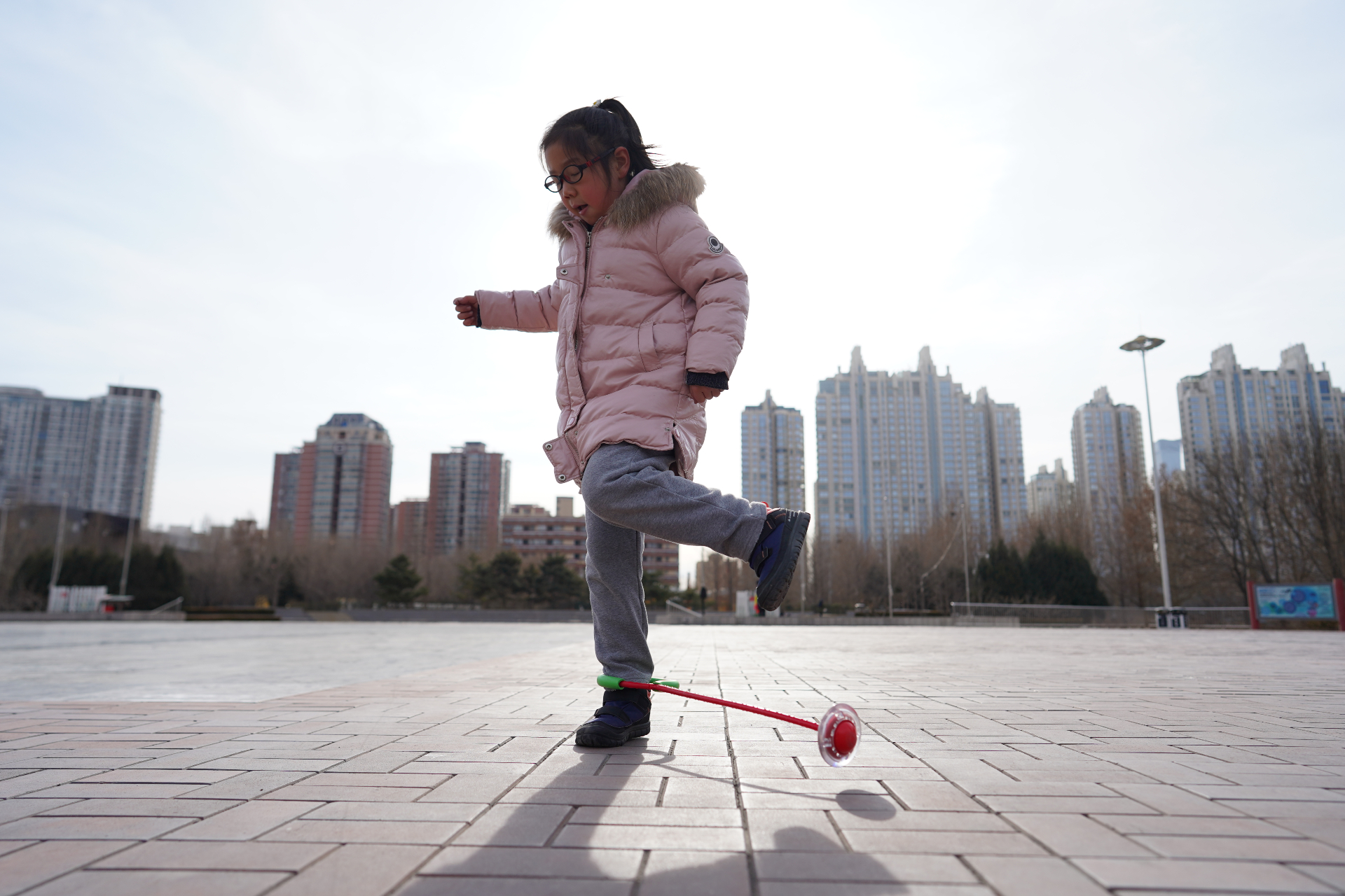 A girl spins a toy on her ankle at a square in China