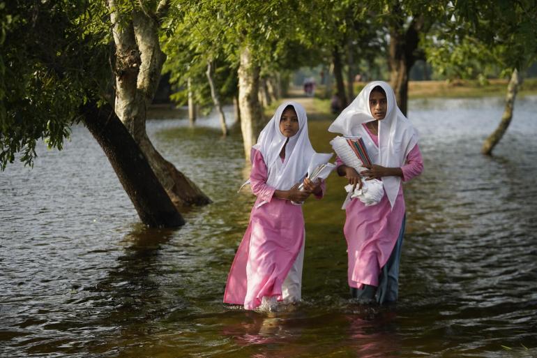 Girls wade through floodwaters on the way to school in Sunamganj, Bangladesh