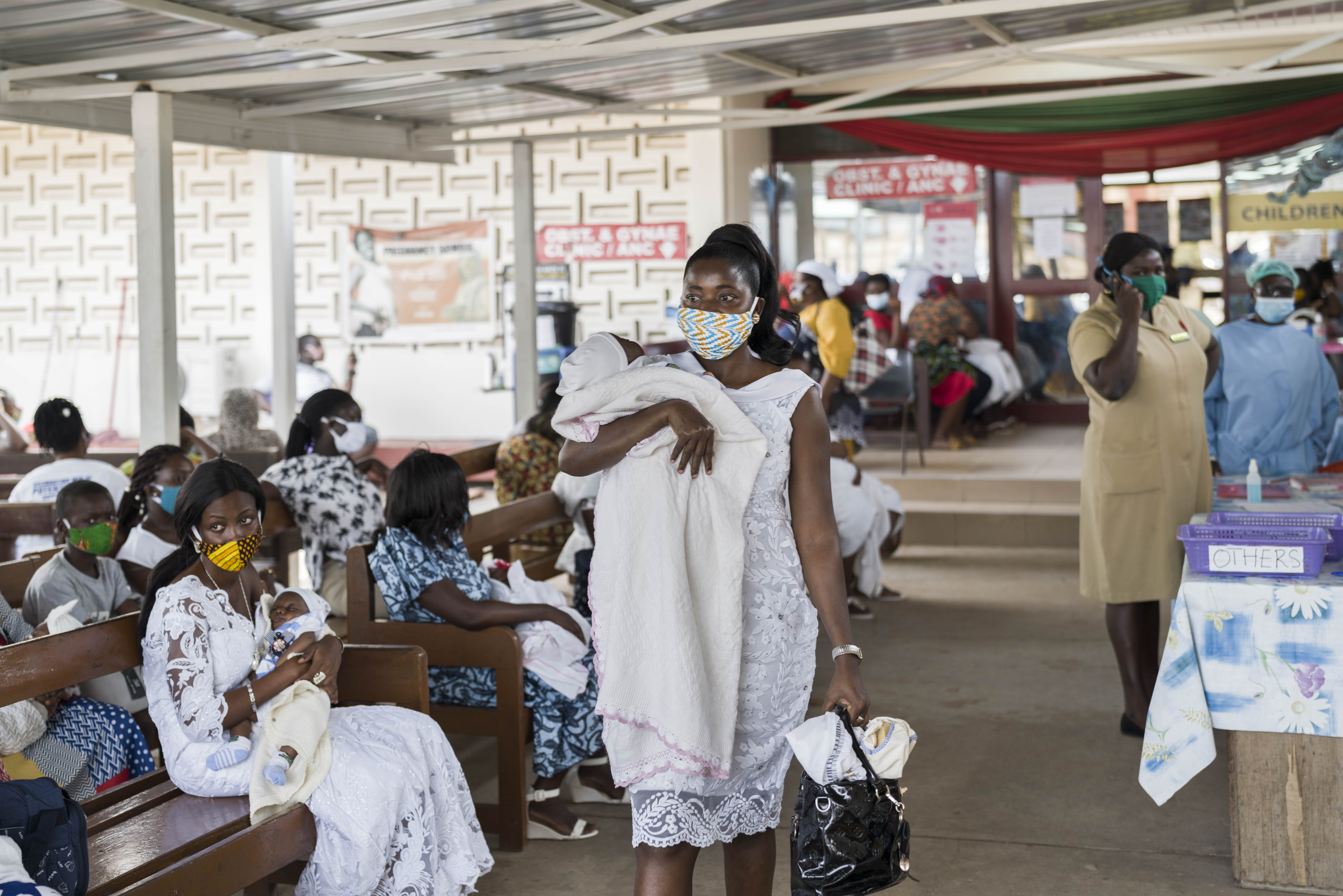 A mother with her newborn walking through a hospital with a mask on due to COVID-19, in Accra, Ghana