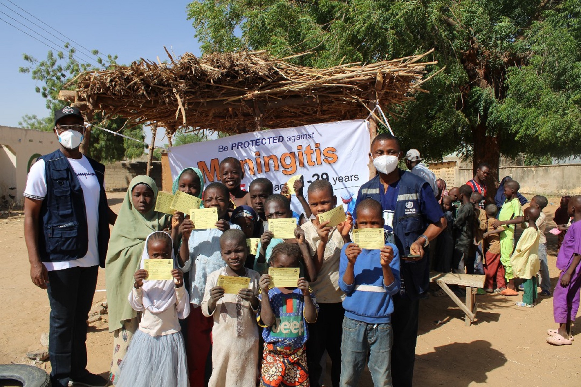 A group of children with two healthcare workers holding their vaccination certificates, in Nigeria