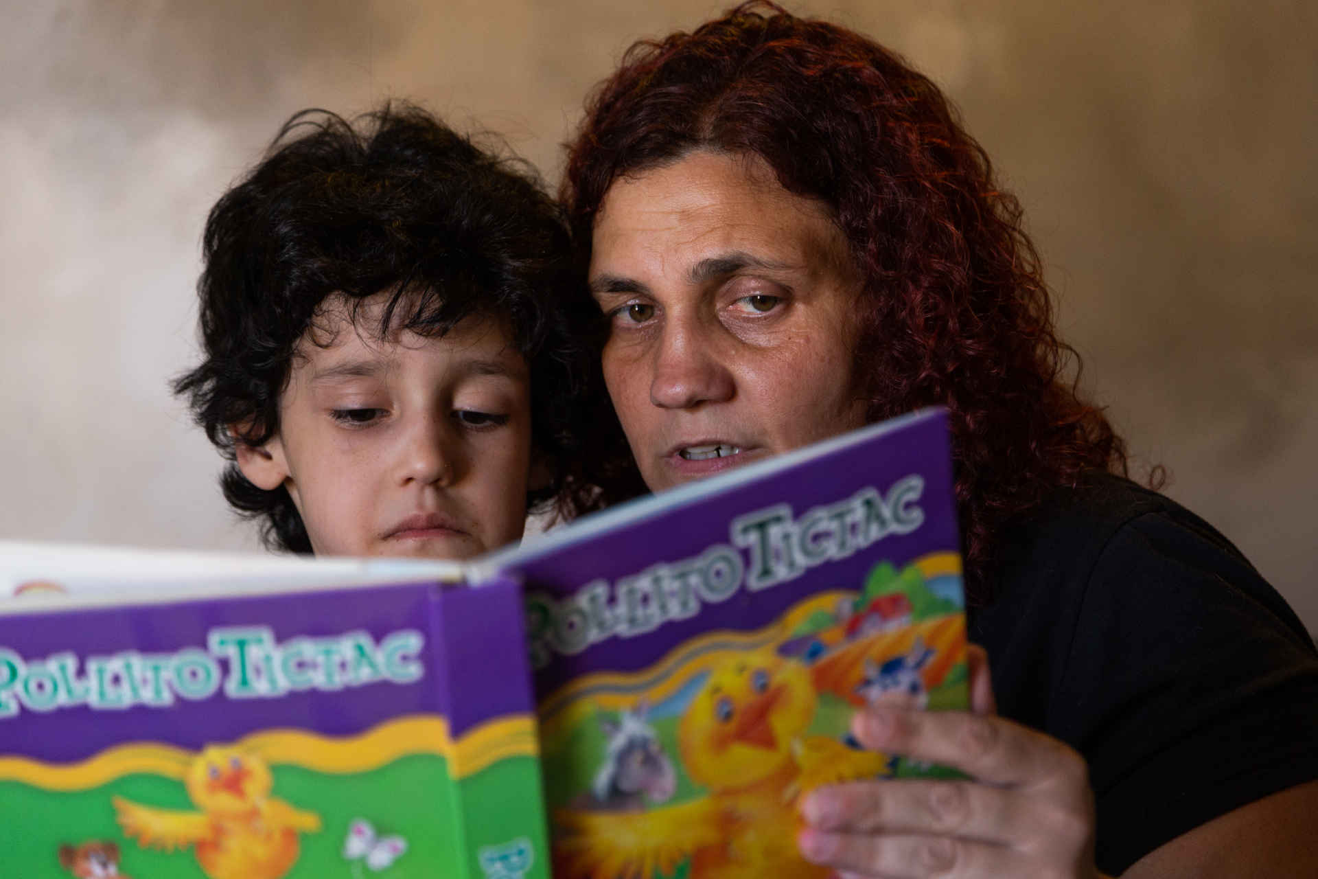 A mother reading a kid's book with her son, in Moreno, Argentina