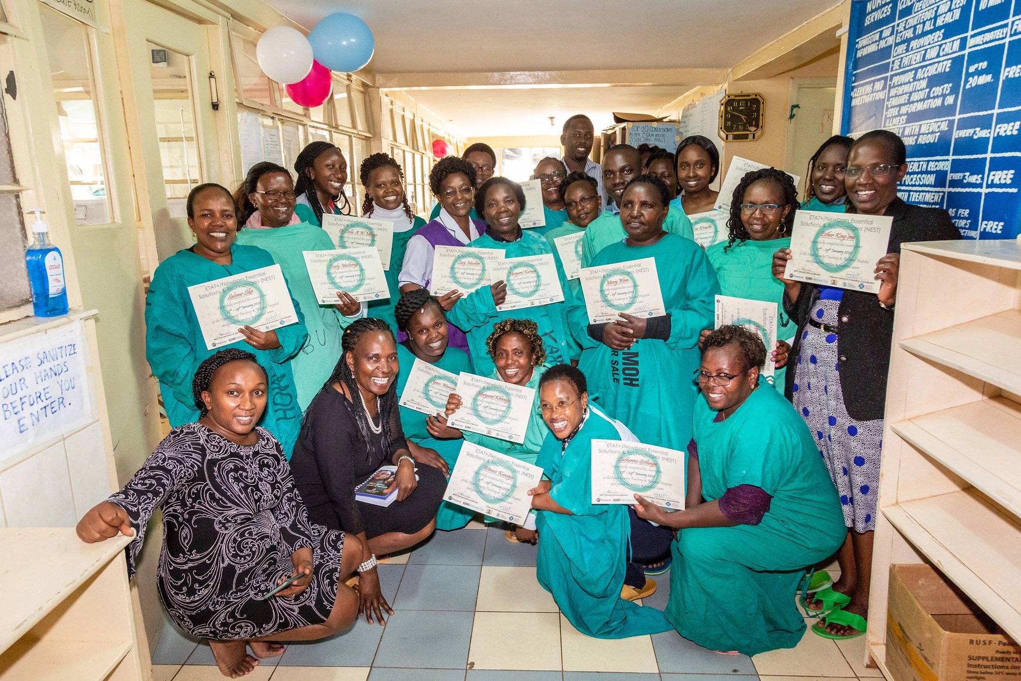 A group of women in medical gowns holding certificates and smiling for a group photo