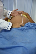 Pregnant woman laying down to have her belly measured, in Colombia