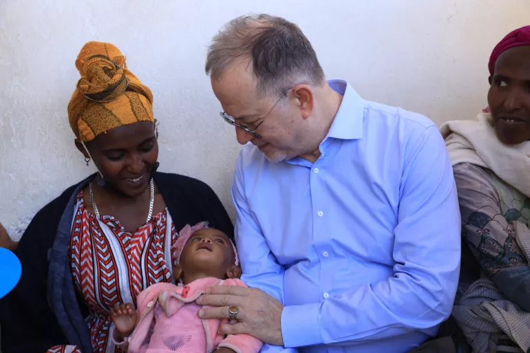 UNICEF Deputy Executive Director Ted Chaiban holding hand on a baby, on his mother's lap in Tigray, Ethiopia
