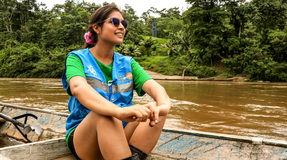A young woman working for UNFPA, cruising on a boat as she smiles on the Peruvian Amazonp